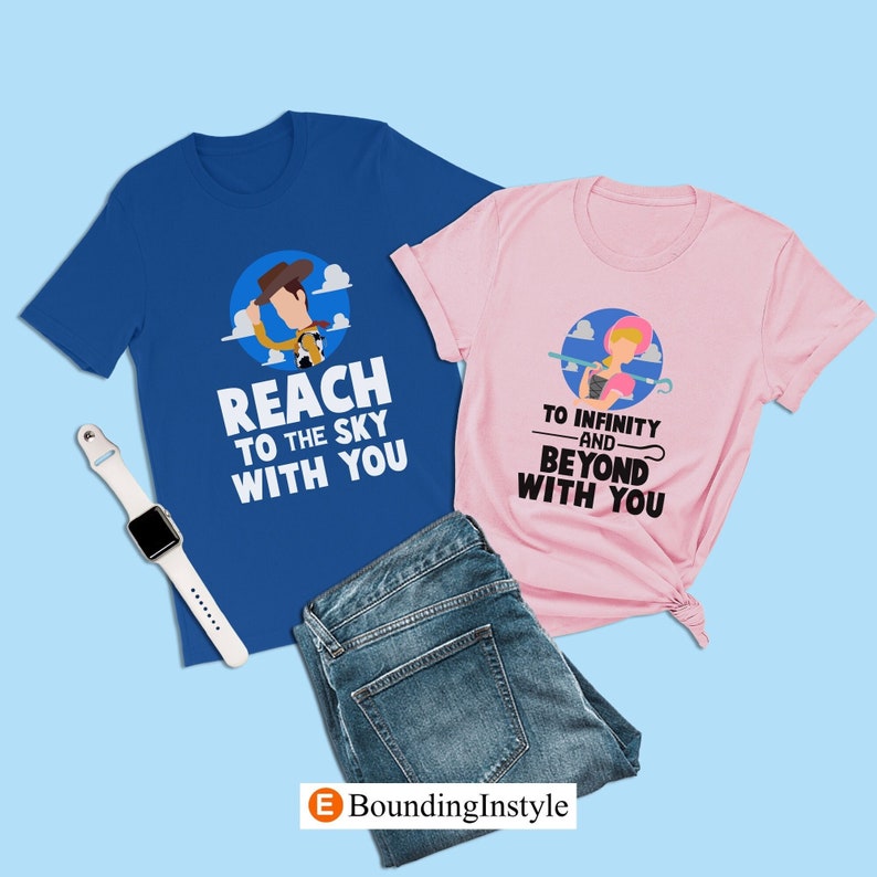 May include: Two t-shirts, one blue and one pink. The blue shirt features a cartoon image of Woody from Toy Story and the text "Reach to the sky with you". The pink shirt features a cartoon image of Jessie from Toy Story and the text "To infinity and beyond with you".