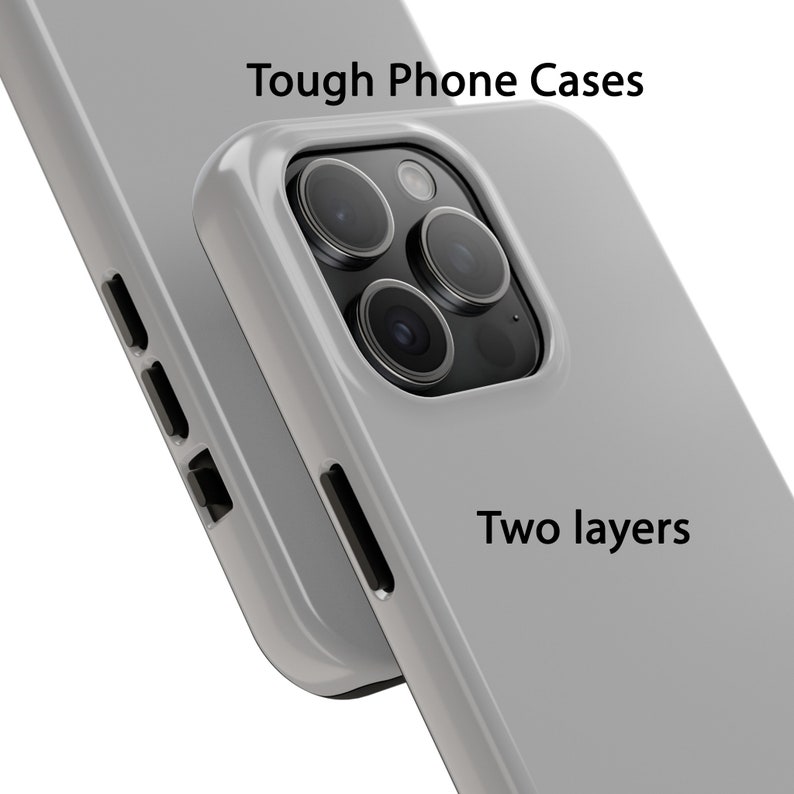 K&ouml;nnte beinhalten: Zwei graue Handyh&uuml;llen mit einem Ausschnitt f&uuml;r das Kameraobjektiv. Der Text "Tough Phone Cases" und "Two layers" ist auf den H&uuml;llen aufgedruckt.