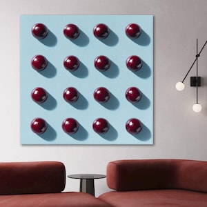 May include: A contemporary artwork showing sixteen dark red spheres arranged in a grid on a light blue canvas. The spheres cast shadows, giving a 3D appearance. The artwork hangs above a rust-coloured sectional sofa and a small black side table.