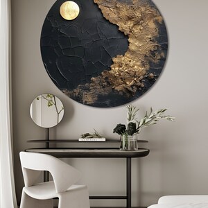 May include: A round black and gold abstract wall art piece with a textured surface. The art piece features a large gold circle in the upper right corner.