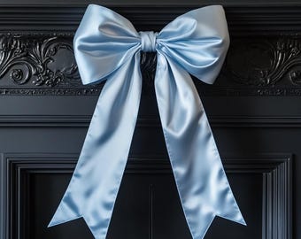 Op de afbeelding: Een grote, lichtblauwe satijnen strik gebonden op een zwart oppervlak. De strik is gebonden met een grote, losse knoop en de uiteinden van de strik zijn lang en vloeiend.