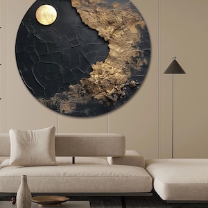 May include: A circular abstract painting with a black and gold color scheme. The painting features a textured surface with a cracked effect. The gold portion of the painting is textured and appears to be raised from the surface. The painting is hanging on a beige wall above a beige couch.