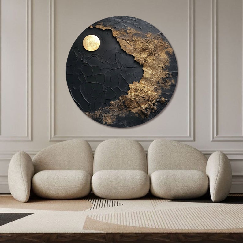 May include: A circular abstract painting with a black and gold color scheme. The painting features a textured surface with a large, round, gold shape in the upper left corner.