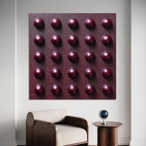 May include: A burgundy-coloured wall art piece with a textured surface and evenly spaced, raised, spherical elements. The artwork is displayed above a modern wooden armchair with a cream-coloured cushion and a small side table with a globe.