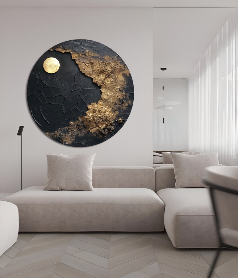 May include: A circular abstract painting with a textured black background and gold accents. The painting features a large, round, gold shape in the center, resembling a sun or moon.