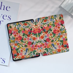May include: A black e-reader case with a floral pattern. The case has a flap that folds over the front of the e-reader.