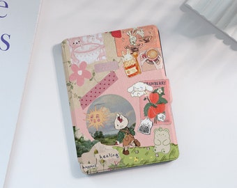 May include: A pink and white notebook cover with a collage of cute illustrations and text. The cover features a sun, a bunny, a strawberry, and the words "healing happens".