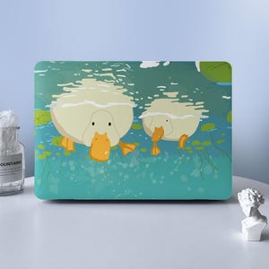May include: A rectangular laptop skin featuring a graphic illustration of two white ducks swimming in teal water with orange beaks and feet, surrounded by green lily pads. The design shows the ducks from a front-facing perspective in the water.