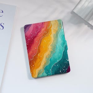 Pode incluir: Capa de tablet colorida com design em aquarela. Apresenta uma mistura vibrante de cores, incluindo rosa, laranja, amarelo, verde-azulado e roxo, com salpicos brancos. O design assemelha-se a ondas.