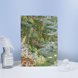 Puede incluir: Una rana verde se sienta en un lecho de nenúfares en una ilustración caprichosa. El fondo presenta un arroyo azul sinuoso, exuberante follaje verde y flores coloridas.