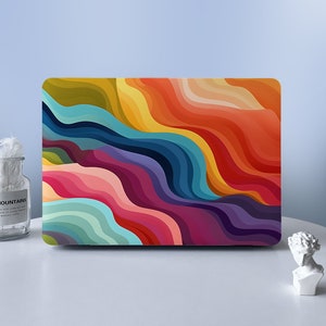 Puede incluir: Una piel de portátil colorida con un diseño abstracto ondulado en tonos de amarillo, naranja, rojo, rosa, azul, verde y morado.