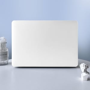 Puede incluir: Una funda para portátil rectangular de color blanco sólido con esquinas redondeadas. La superficie es lisa y mate, lo que proporciona un aspecto limpio y uniforme. Esta carcasa protectora está diseñada para cubrir la tapa exterior.