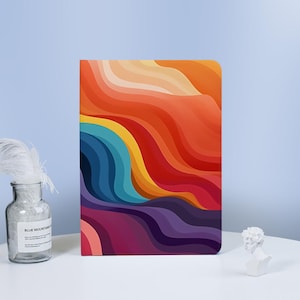 以下が含まれることがあります： オレンジ、イエロー、ブルー、パープル、レッドのグラデーションで波打つ抽象的なデザインが施されたカラフルなノートブックです。