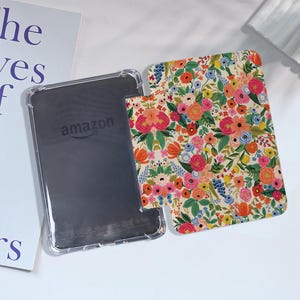 May include: A clear case with a floral pattern for an Amazon Kindle e-reader. The case has a white background with colorful flowers and leaves.