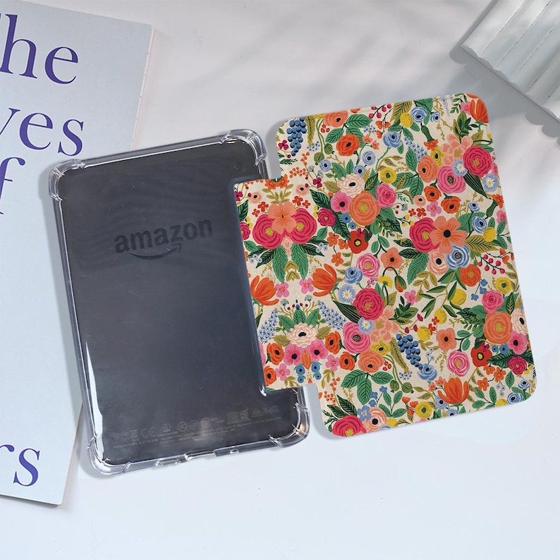 May include: A clear case with a floral pattern for an Amazon Kindle e-reader. The case has a white background with colorful flowers and leaves.