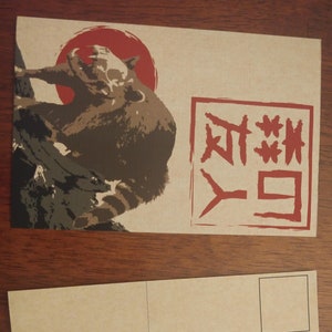 Może przedstawiać: Brązowa pocztówka z ilustracją brązowego i czarnego szopka na przodzie. Szop stoi na gałęzi z czerwonym słońcem za nim. Tekst "夜" jest nadrukowany na czerwono na przodzie pocztówki.