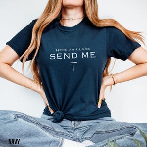 May include: A navy blue t-shirt with the text "Here am I Lord Send Me" and a cross.