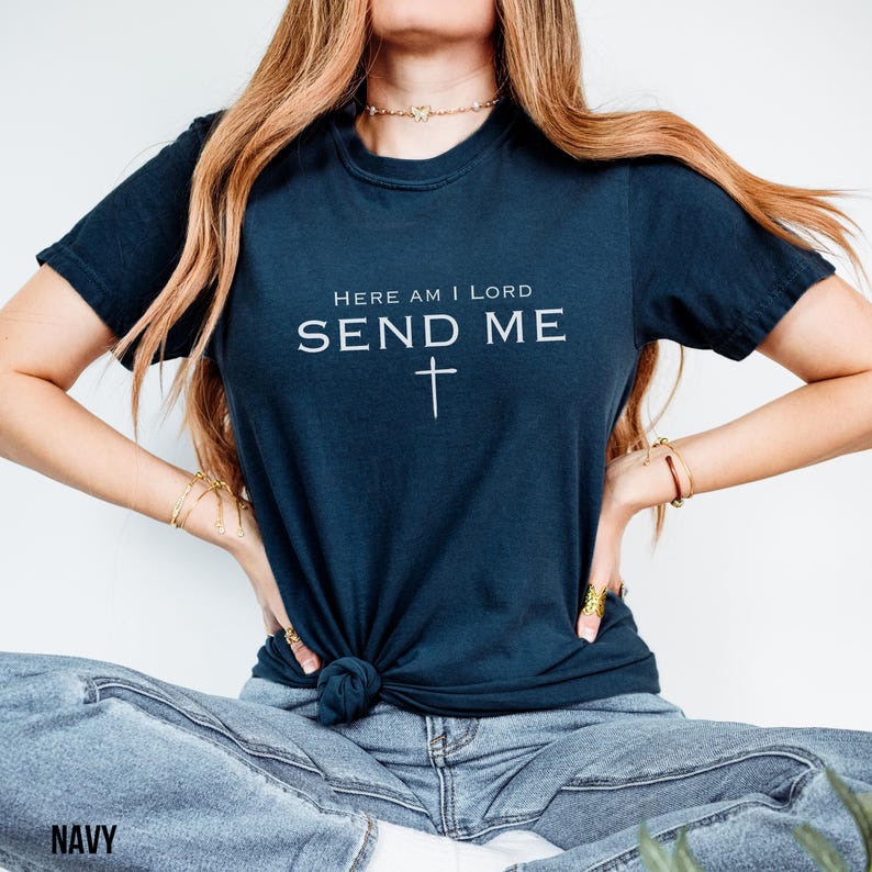 May include: A navy blue t-shirt with the text "Here am I Lord Send Me" and a cross.
