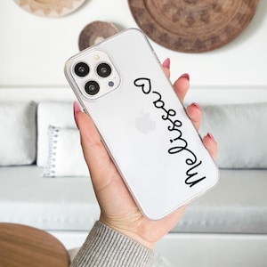 May include: A clear phone case with a black heart and the name "Melissa" written in cursive.