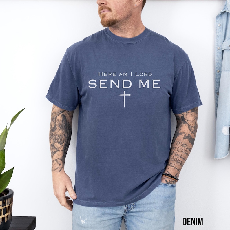 May include: A navy blue t-shirt with the text "Here am I Lord Send Me" and a white cross.