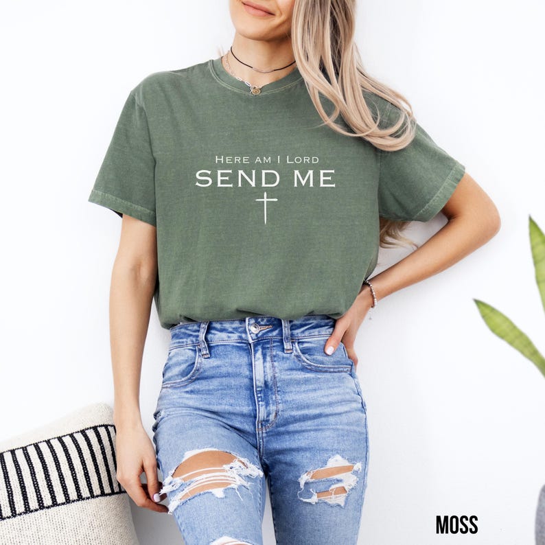 May include: A green t-shirt with the text "Here am I Lord Send Me" and a cross underneath. The shirt is made of a soft, comfortable material and has a relaxed fit.