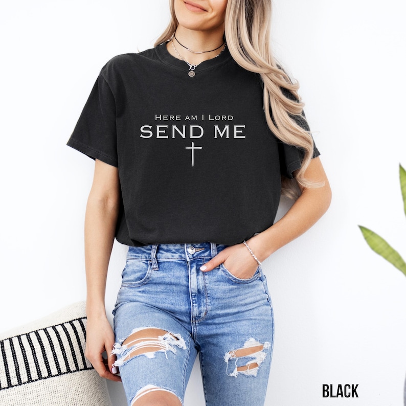 May include: A black t-shirt with the text "Here am I Lord Send Me" and a white cross.