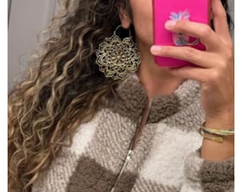 May include: Gold-toned large hoop earrings with a delicate mandala design. The earrings are lightweight and have a bohemian style.