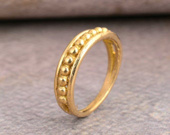 May include: A gold ring with a beaded design. The ring is simple and elegant.