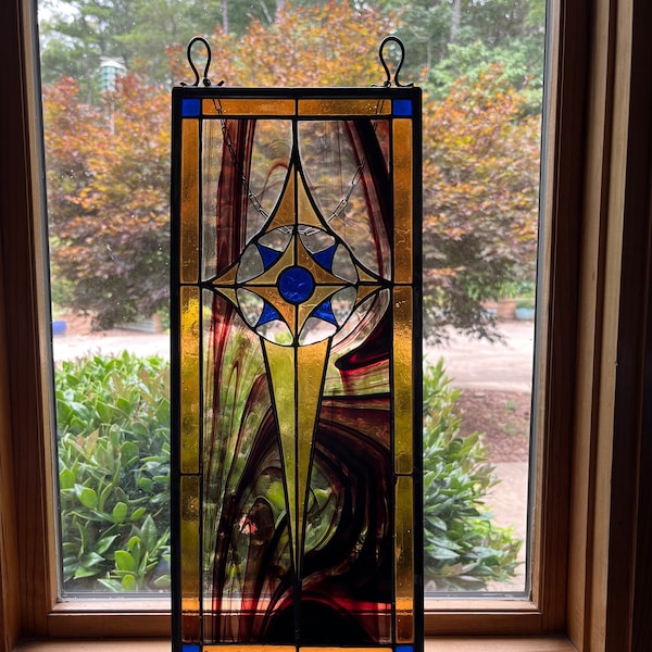 Stained Glass panel for window or wall display. 7 inches wide x 17 inches high, ambers,marron, & blue glass give this art a classic impact.