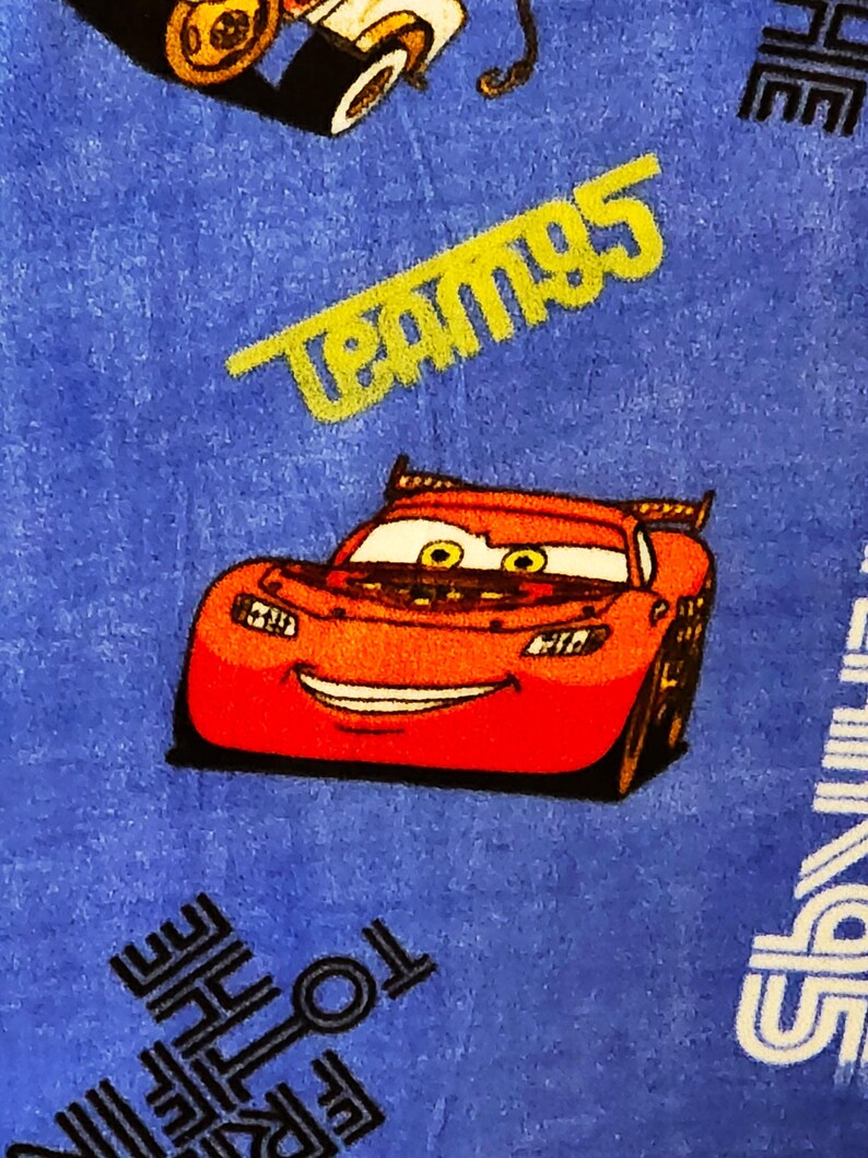 May include: Red cartoon race car with a big smile on a blue background with the text "Team 95" in yellow and black text.