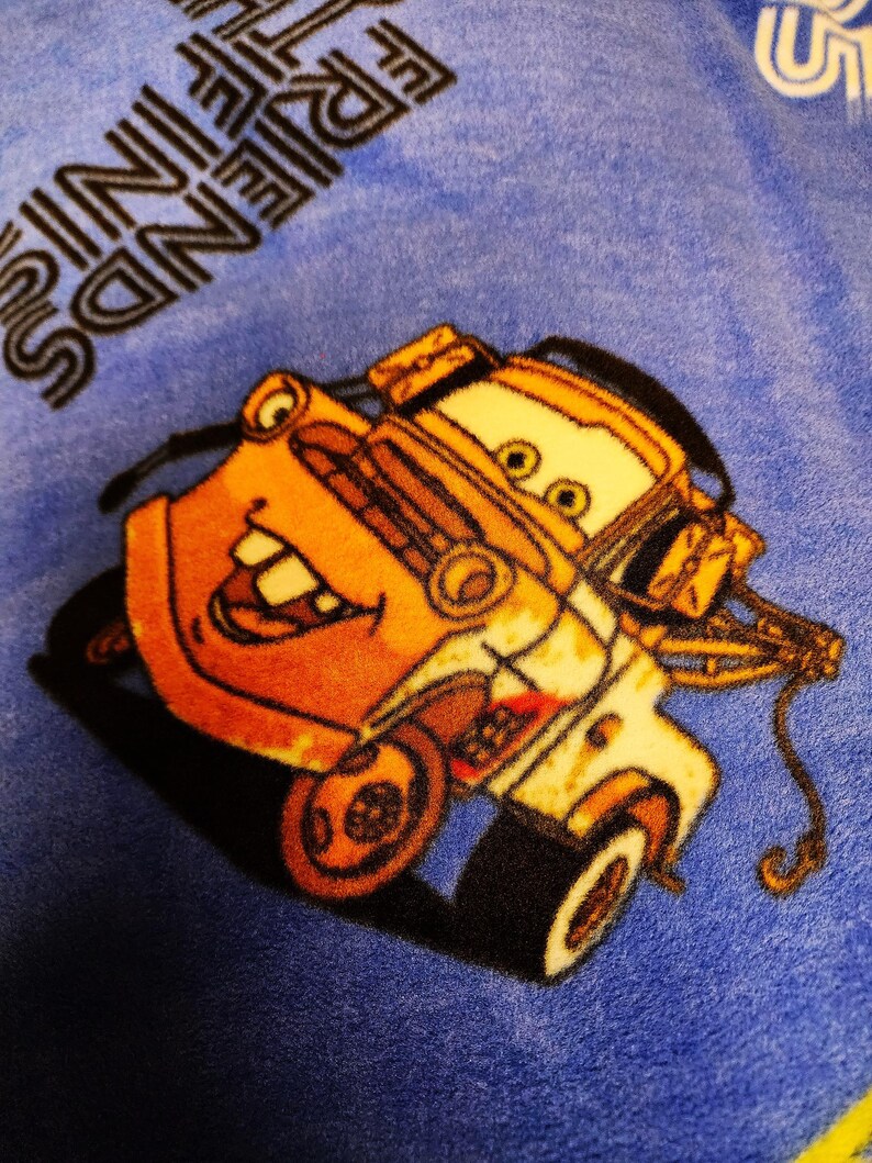 May include: A yellow and orange tow truck with a smiling face, on a blue background with the text "Friends are the best" in black.