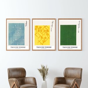 Puede incluir: Tres impresiones enmarcadas con texto japonés y diseños abstractos. Las impresiones están en un marco de madera claro y están colgadas en una pared blanca. Las impresiones son de color azul y blanco, amarillo y blanco, y verde y blanco.