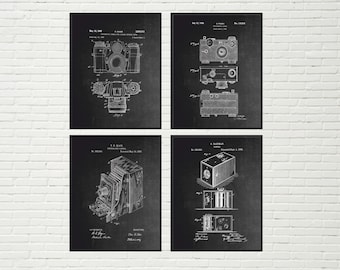 Op de afbeelding: Set van vier vintage camera patent prints in zwart-wit. Elke print toont een ander cameradesign en bevat het patentnummer en de datum.