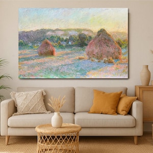 Può includere: Un dipinto che rappresenta un campo con due grandi covoni di fieno in primo piano. I covoni di fieno sono di colore rosa chiaro e il campo è di colore blu chiaro e verde. Il cielo è di colore blu chiaro e ci sono alberi sullo sfondo.