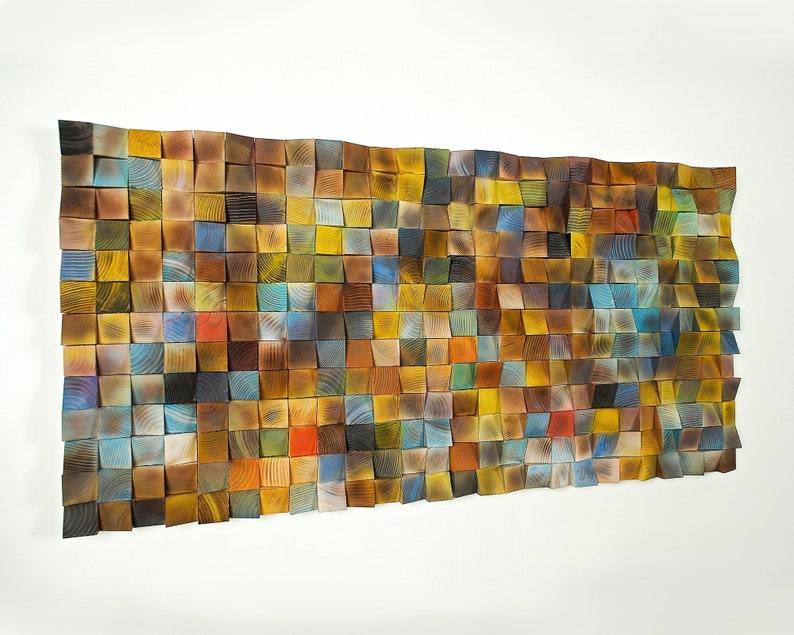 May include: A wall art piece made of wood blocks in various shades of brown, blue, yellow, and red. The blocks are arranged in a grid pattern and create a textured, abstract design.