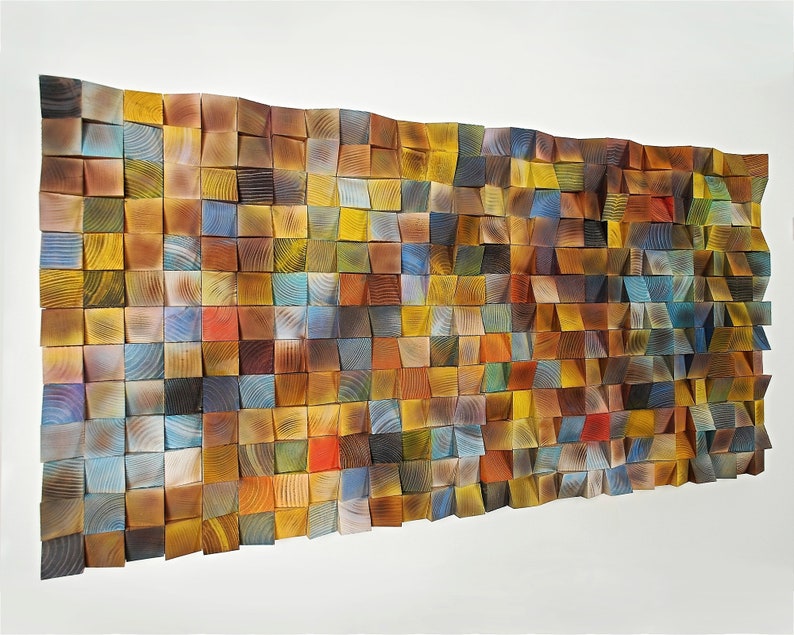 May include: A wall art piece made of wood blocks in various shades of brown, yellow, blue, and green. The blocks are arranged in a grid pattern and create a textured, abstract design.