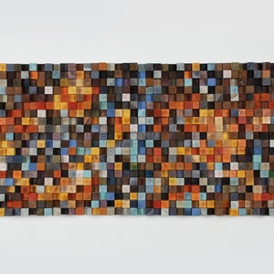 Könnte beinhalten: Ein Wandkunstwerk aus kleinen Holzkacheln in verschiedenen Blautönen, Grüntönen, Orangetönen und Brauntönen. Die Kacheln sind in einem Gittermuster angeordnet und erzeugen einen Mosaik-Effekt.
