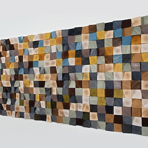 May include: A large wooden wall art piece made from many small, square blocks. The blocks are painted in various colours, including brown, blue, yellow, and grey. The arrangement creates a textured, three-dimensional effect, suitable for home decor, measuring approximately 150cm x 75cm.