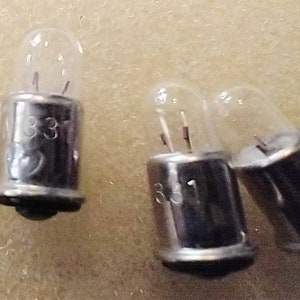 May include: Three clear glass light bulbs with silver metal bases. The bases are marked with the number "33".
