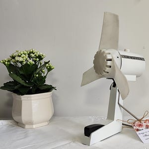 Puede incluir: Ventilador de mesa vintage blanco con una base de plástico blanco y una cuchilla de plástico blanco. El ventilador tiene una etiqueta negra que dice "ОРЕВИТА".