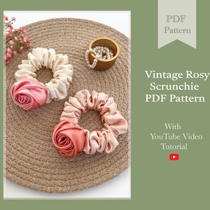 Könnte beinhalten: Zwei rosa und weiße Scrunchies mit Rosen-Detail. Die Scrunchies liegen auf einer gewebten Matte. Das Bild enthält den Text "Vintage Rosy Scrunchie PDF Pattern with YouTube Video Tutorial".