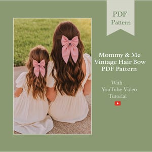 Op de afbeelding: Twee personen met lang bruin haar dragen bijpassende roze haarstrikken. Ze zitten met hun rug naar de camera en dragen witte jurken. De afbeelding bevat de tekst "Mommy & Me Vintage Hair Bow PDF Pattern" en "With YouTube Video Tutorial."