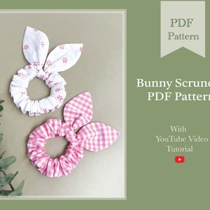 May include: Two bunny scrunchies with fabric ears. One is white with red floral print, the other is pink gingham. The image includes text that reads "Bunny Scrunchie PDF Pattern" and "With YouTube Video Tutorial."