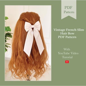 Op de afbeelding: Een lichtbeige strik is bevestigd aan lang, golvend roodbruin haar. De strik is een vintage Franse slanke haarstrik. De afbeelding bevat de tekst "PDF Pattern" en "Vintage French Slim Hair Bow PDF Pattern" met een YouTube-videotutorial.