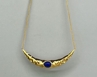 Gold necklace with a lapis lazuli medallion. Ethnic necklace with a large hammered medallion and a lapis lazuli. Gold and blue stone jewelry.