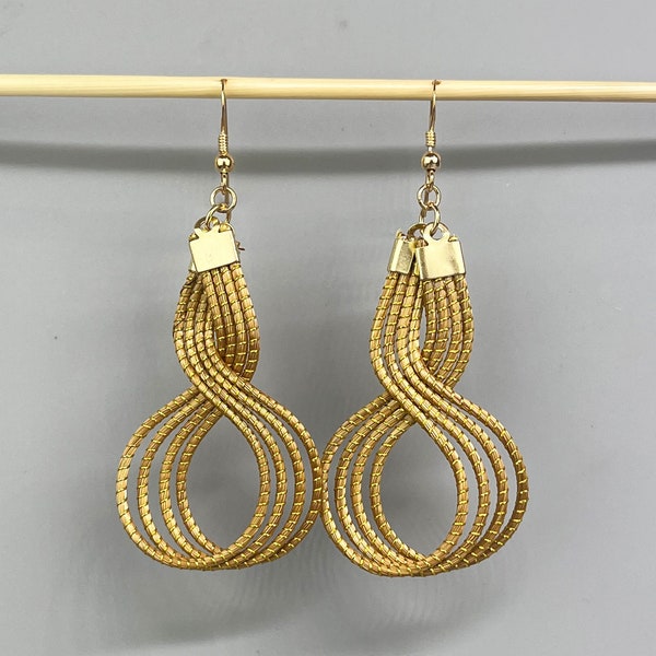 Jolies boucles d'oreilles en forme du symbole infini fabriquées en Capim dourado avec un crochet argent 925. Bijoux en or végétal.