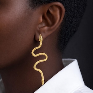 Oorbellen in de vorm van een slang van goudkleurig staal. Lange, realistische oorringen in de vorm van een slang van 18 karaats goudkleurig roestvrij staal. Etnische sieraden.