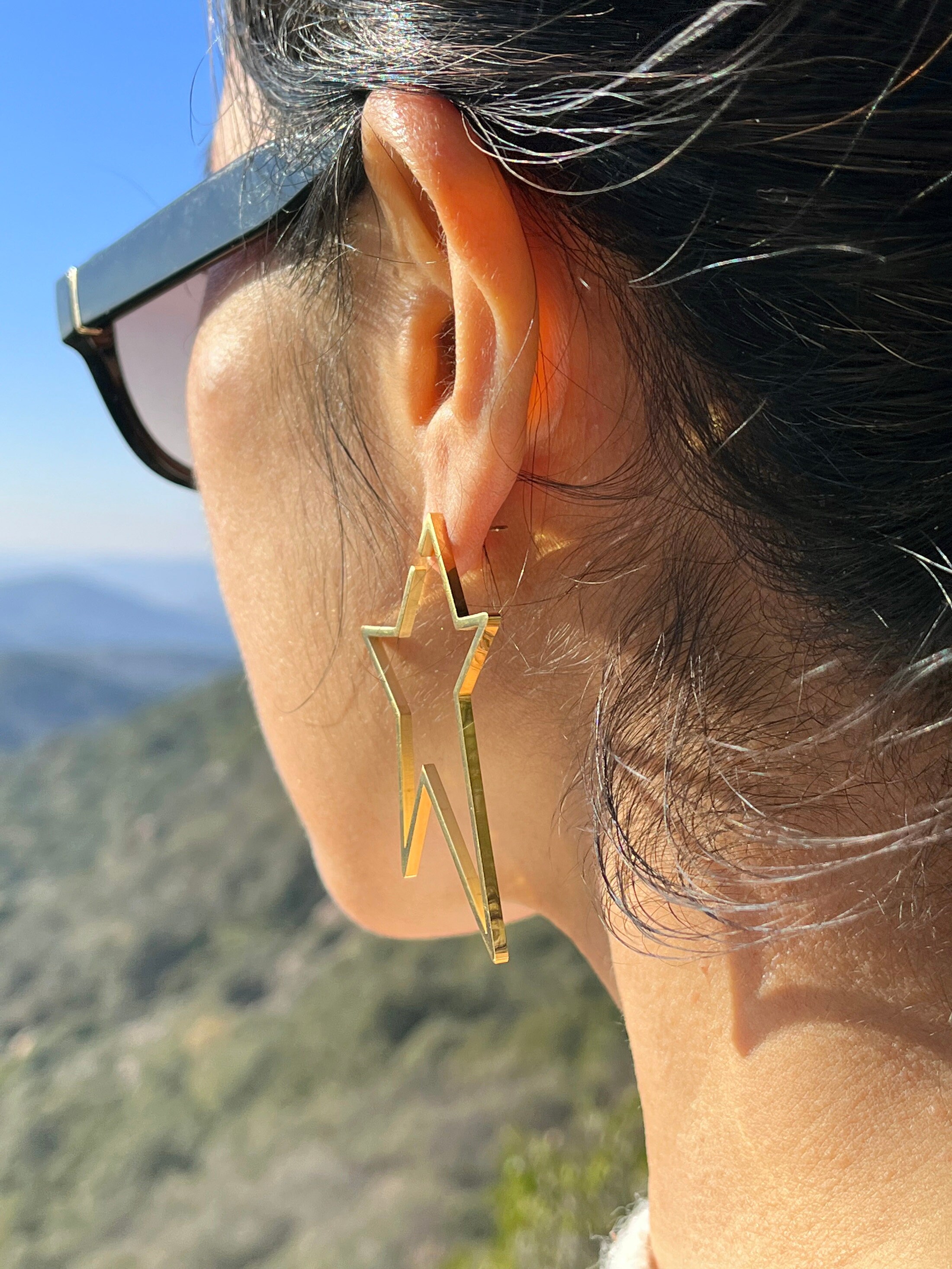 Large star-shaped hoop earrings. Gold earrings in stainless steel. Modern hoop earrings. Shooting star earrings.