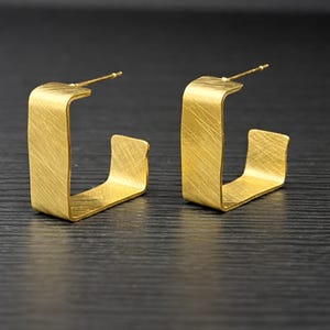 Fyrkantiga örhängen i rostfritt stål. Geometriska örhängen i matt guld i borstat stål.