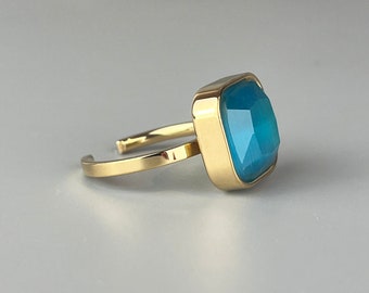 Verstelbare, verstelbare roestvrijstalen ring. Vierkante gouden ring met een blauwe steen. Bioux-vrouw als kerstcadeau. Vierkant opaalmodel.